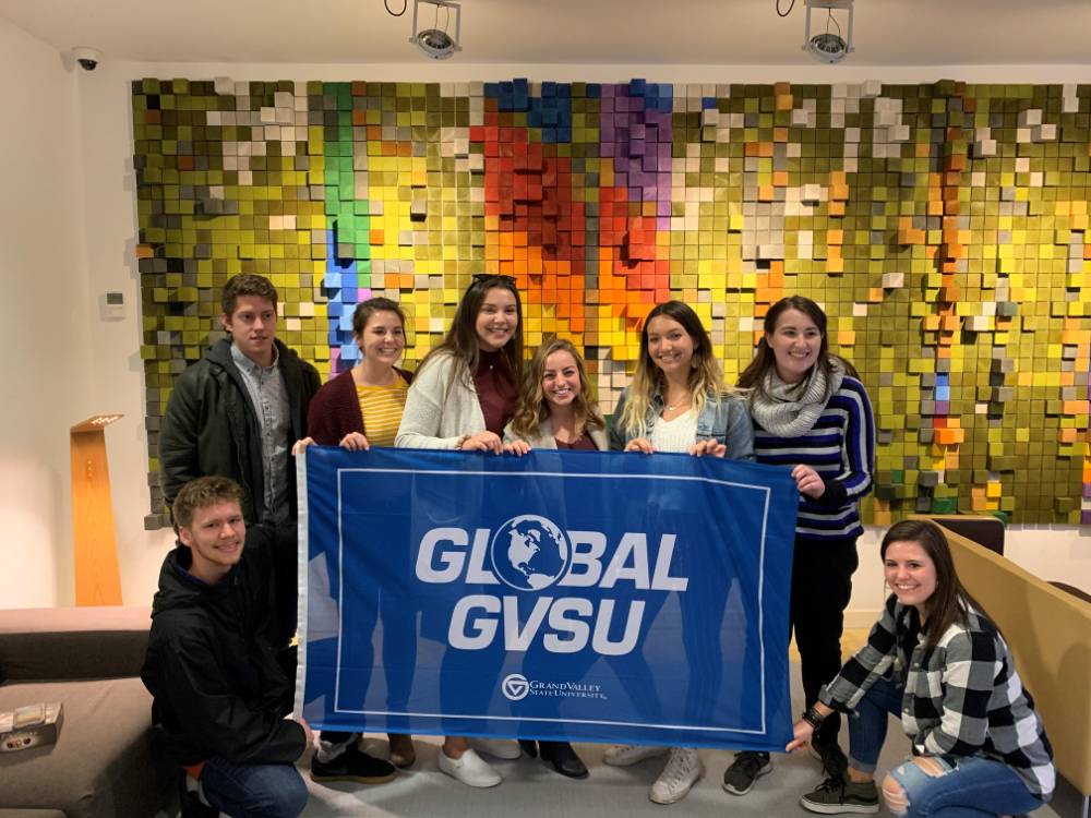 Eight GVSU students holding Global GVSU flag at museum in Bilbao, Spain